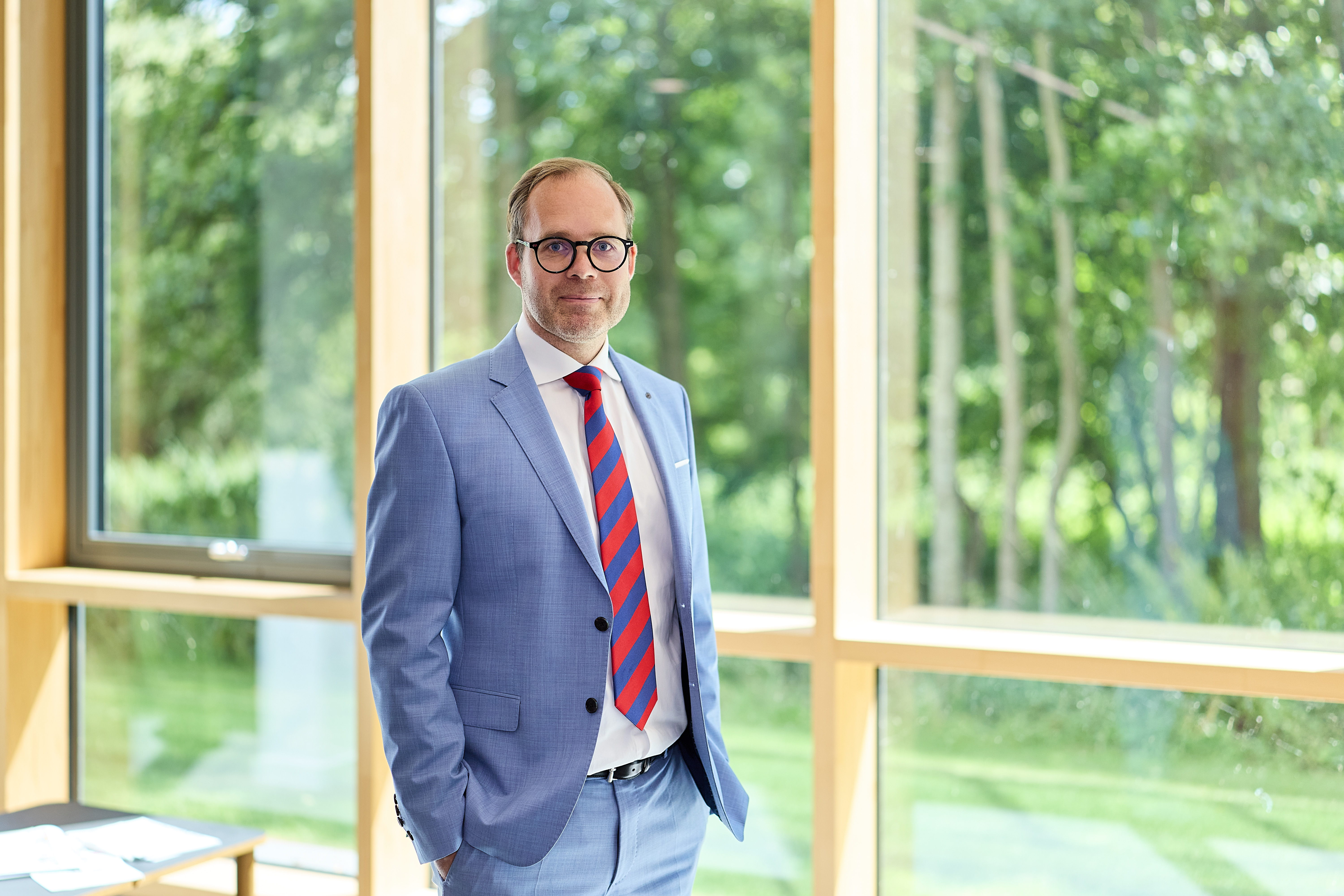 Sven Meier steht vor einer Glascheibe und guckt in die Kamera