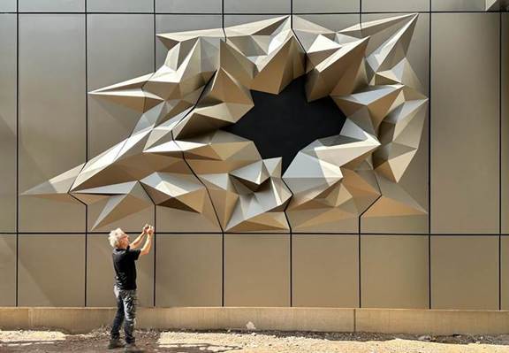 Matthias Lehamnn steht vor einem Kunstwerk, dass ein großes Loch in Papierform darstellt